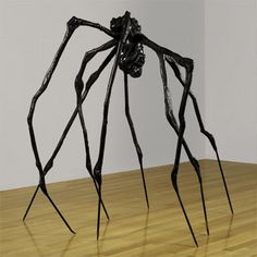 a large spider sculpture sitting on top of a wooden floor next to a white wall