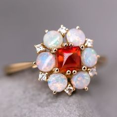 an opal and diamond cluster ring on top of a gray surface with other opals surrounding it