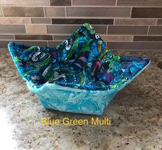 blue green multicolored bowl on counter top with tile back splashing in the background