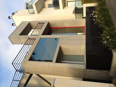 a modern house with balconies on the top floor and red door in front