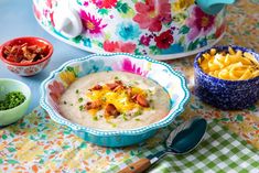 two bowls of food on a table with other dishes and utensils next to them