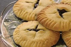 four blueberry pies sitting on top of a glass plate