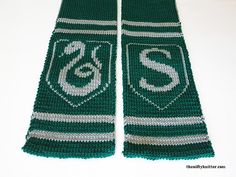 two green and white knitted scarfs with the letter s on them