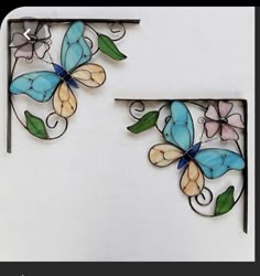 two metal butterfly wall hangings with green leaves and pink flowers on each one side