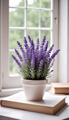 a white bowl with purple flowers in it on a table next to a book and window