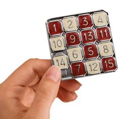 a hand holding up a red and white calculator with numbers on it's side