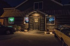 an old log cabin is lit up at night with lights on the door and windows