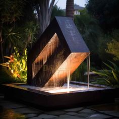 a water fountain in the shape of a house with lights on it's sides