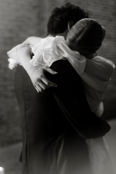 a man and woman hugging each other in black and white