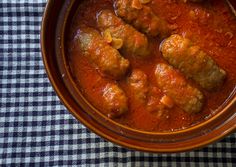 some meatballs are in a red sauce on a checkered tablecloth with a black and white napkin