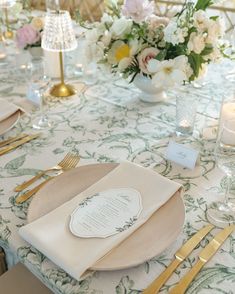 the table is set with place settings and gold utensils for guests to eat