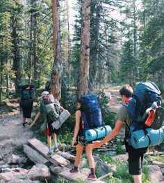 three people with backpacks walking up a rocky trail