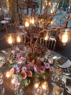 the table is set with candles and flowers in vases, plates and silverware