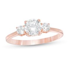 three stone engagement ring in rose gold with an oval diamond center and two round diamonds on the side