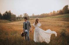 a bride and groom are walking through the field