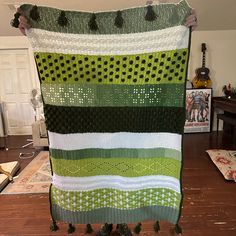 a large green and white crocheted blanket sitting on top of a wooden floor