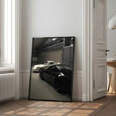 a black sports car in front of a mirror on the wall next to a radiator