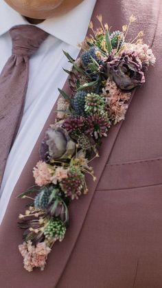 a man wearing a suit and tie with flowers attached to it's lapel