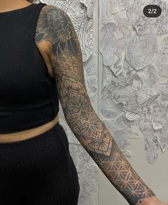 a woman with a tattoo on her arm and arms is standing in front of a wall