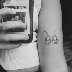 a woman holding a cell phone with a tattoo on her arm and two little birds