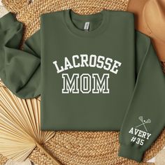 a sweatshirt with lacrosse mom on it sitting next to some straws and a fan