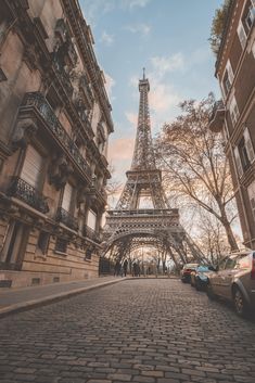 the eiffel tower in paris, france with cars parked on the side walk