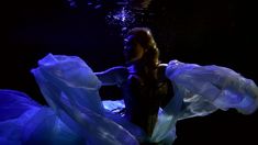 a woman in a blue dress under water