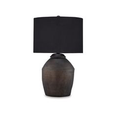 a lamp with a black shade on top of it and a white wall behind it