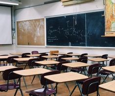 an empty classroom with desks and chalkboard