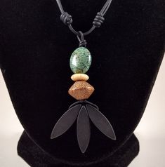 "The variscite, bone, wood, horn, and black onyx pendant is 2.85 inches in length on natural black polished round leather. The variscite bead is 13 by 17 mm and the onyx beads are 8 by 26 mm. The necklace is adjustable from 18 inches to 34 inches by sliding the knots.  Variscite is a hydrated aluminium phosphate mineral. It is a relatively rare phosphate mineral. It is sometimes confused with turquoise; however, variscite is usually greener in color. The green color results from the presence of Handmade Black Earthy Jewelry, Handmade Black Nature-inspired Jewelry, Handmade Nature-inspired Black Jewelry, Adjustable Black Earthy Jewelry, Unique Black Leather Jewelry, Black Hand-tooled Bohemian Jewelry, Unique Hand Tooled Black Jewelry, Black Hand Tooled Bohemian Jewelry, Black Bohemian Hand-tooled Jewelry