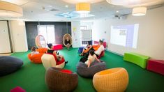 people sitting on bean bag chairs in an office with green flooring and white walls