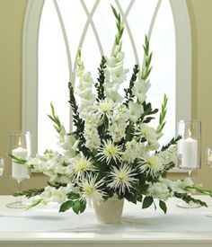 a vase filled with white flowers sitting on top of a table in front of a window