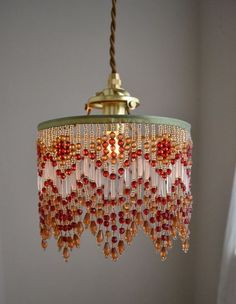 a chandelier hanging from a ceiling with red beads and gold trimmings