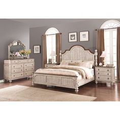 a bedroom scene with focus on the bed and dressers, mirror and window frames