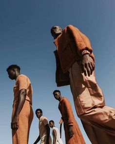 four men in orange clothing standing next to each other with their hands on their hipss