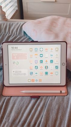 an ipad sitting on top of a bed next to a pink pillow and white pillows