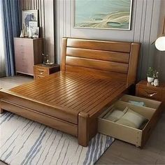 a wooden bed with drawers underneath it in a bedroom next to a painting on the wall