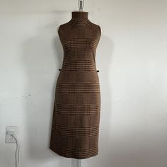 "Introducing a true vintage gem from the 1970s - the brown and gold glittery houndstooth pattern sleeveless dress by Sharagano Paris. This stunning dress is a rare find that will add a touch of retro glamor to your wardrobe. This dress features a unique houndstooth pattern in a warm brown and gold glittery hue that shimmers in the light. The sleeveless design allows for easy movement, while the fitted silhouette accentuates your curves for a flattering fit. The dress also features a high necklin Retro Brown Midi Dress, Retro Sleeveless Winter Dresses, Retro Brown Dress For Fall, Fitted Brown Sleeveless Dress For Fall, Retro Sleeveless Brown Dress, Retro Brown Sleeveless Dress, 1970s Fitted Brown Dress, Vintage Plaid Sleeveless Dress, Fitted Brown 1970s Dress