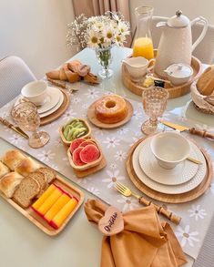 the table is set with bread, fruit, and other breakfast foods for two people