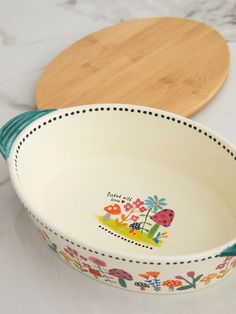 the bowl is decorated with colorful flowers and ladybugs on it, along with a cutting board