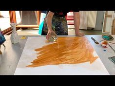 a person is painting an orange piece of paper on a table with scissors and paint