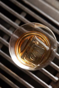 a glass filled with liquid sitting on top of a metal grate