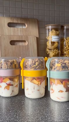 three jars filled with food sitting on top of a counter next to plastic utensils