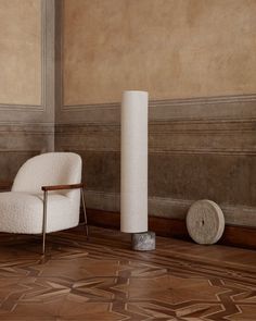 a white chair sitting on top of a wooden floor next to a tall pillar in a room