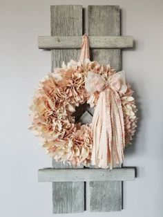 a wreath is hanging on the wall next to a cross and some wood planks