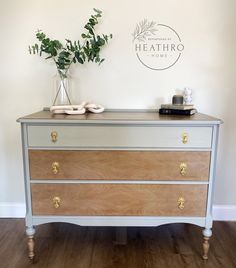 a white and wood dresser with some plants on it's top, next to a sign that says heathro