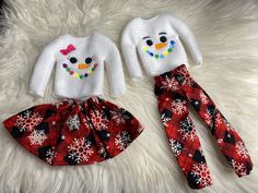 two children's snowman christmas outfits sitting on top of a white furnish