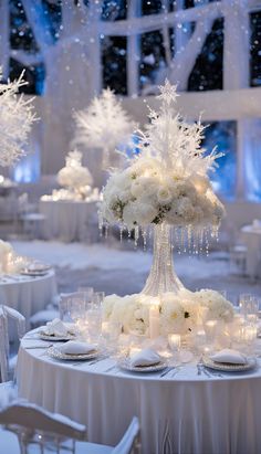 a table with white flowers and candles on it in the middle of a room filled with snowflakes