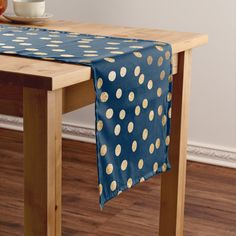 a table with a blue and gold polka dot table runner on it next to a bowl of fruit