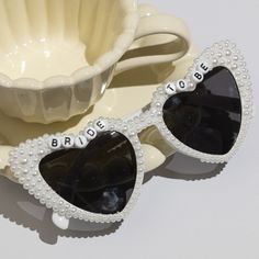 two pairs of sunglasses with the words bride and groom written on them next to a bowl